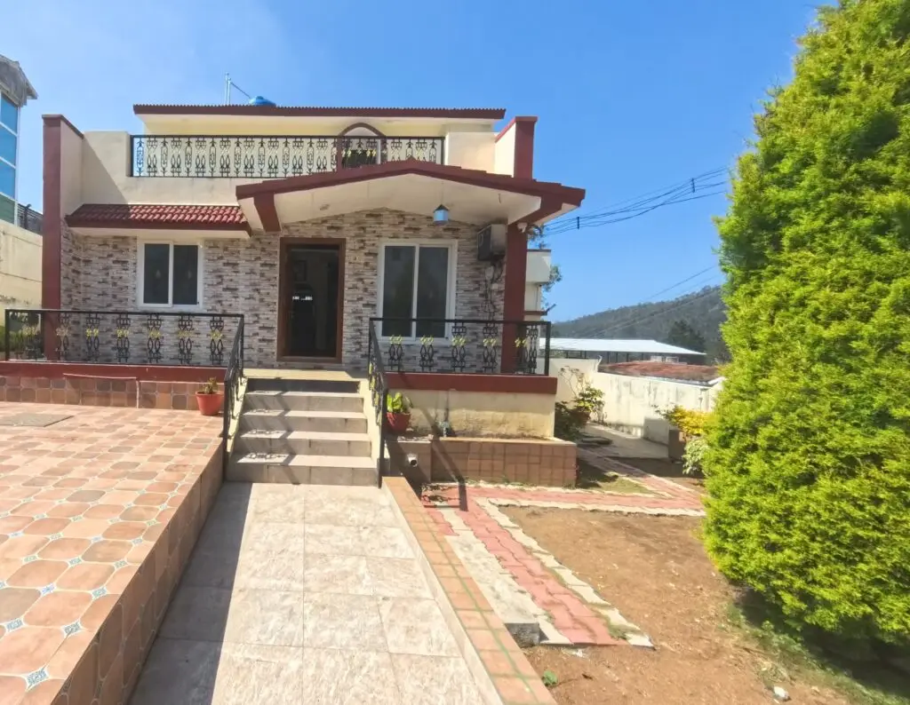 Beautiful homestay in Yercaud with a modern two-story design, tiled front patio, garden area, and mountain view under a clear blue sky.